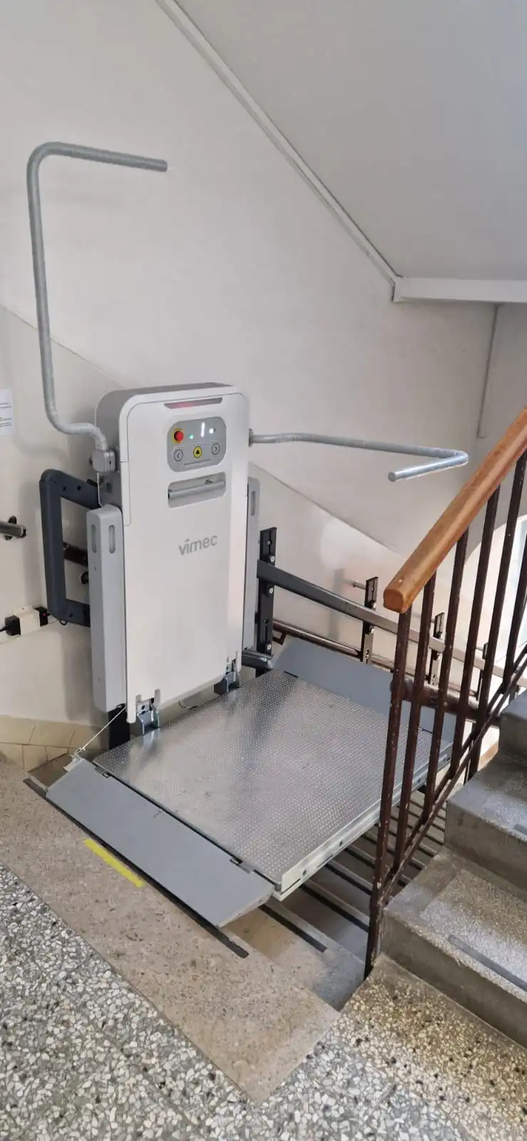 Plateforme élévatrice Vimec repliée contre un mur en bas d'un escalier intérieur