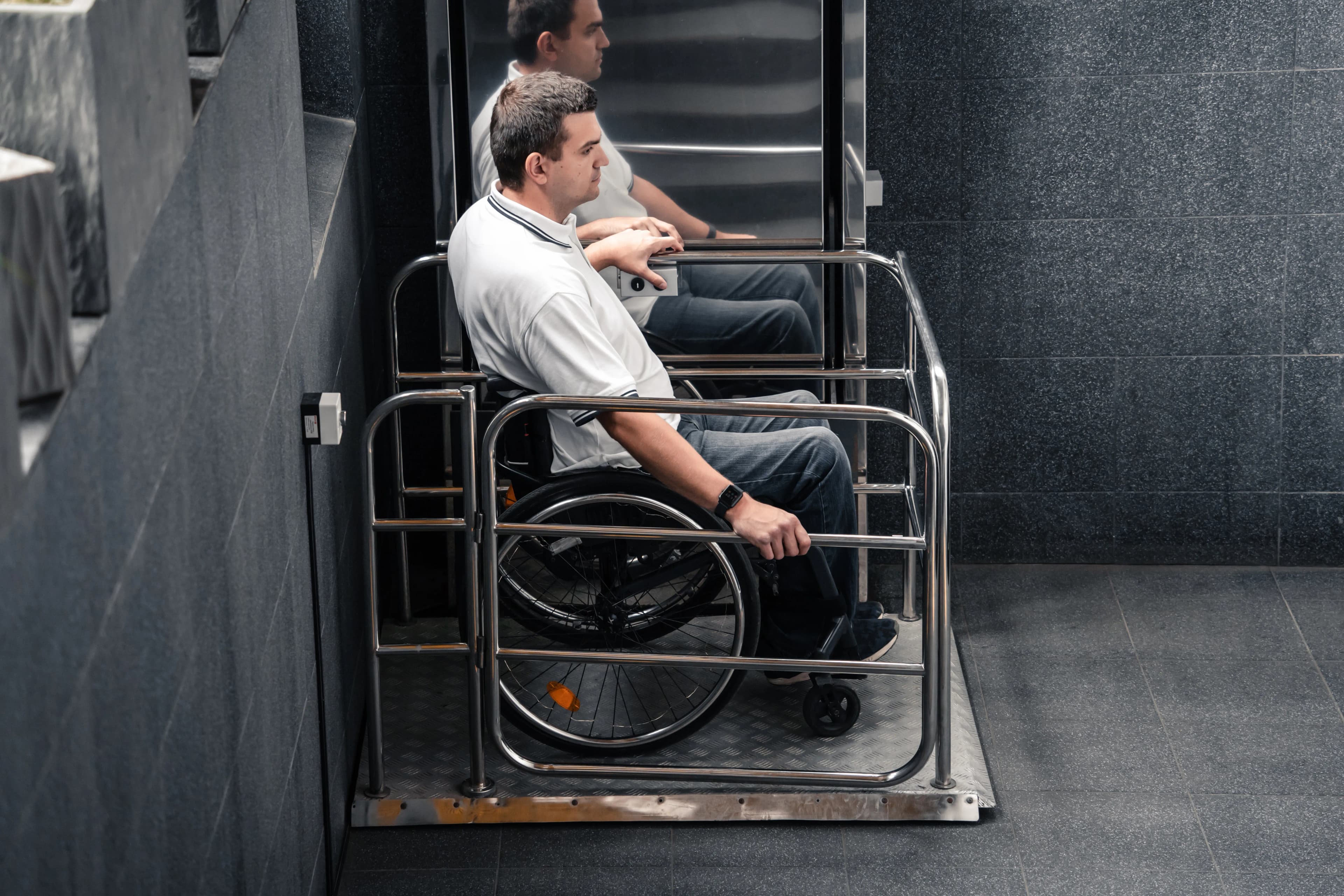Personne en fauteuil roulant utilisant une plateforme élévatrice à barres en acier inoxydable