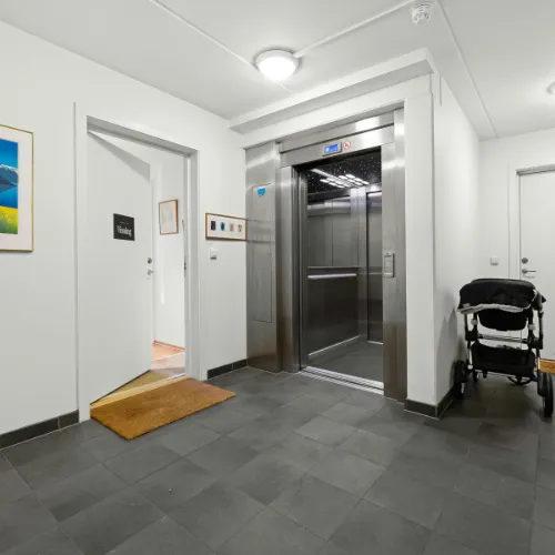 Ascenseur résidentiel aux portes ouvertes dans le couloir d'un appartement avec poussette