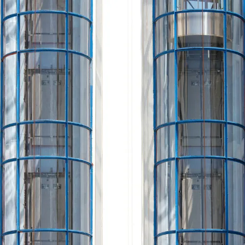 Deux tours d'ascenseurs panoramiques cylindriques avec structure métallique bleue en façade